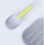 Close-up of the FurryFable pet food spoon in green and gray, showing comfortable handle